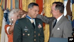 FILE - President George Bush lends his glasses to first lady Barbara Bush as she pins a Medal of Freedom on Gen. Colin Powell, chairman of the Joint Chiefs of Staff, during a White House ceremony, July 3, 1991. 