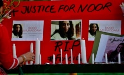 A women's rights activist places a candle beside a poster with the pictures of Noor Mukadam, who was recently beheaded, during a candle light vigil to pay tribute to Noor and other domestic violence victims, in Islamabad, Pakistan, July 25, 2021.