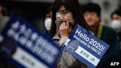 People queue to see the Tokyo 2020 Olympic flame on display outside the railway station in Tono, Iwate prefecture, March 22, 2020.