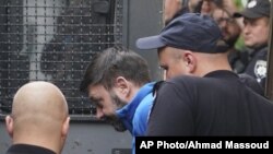 Kirill Vyshinskiy, pimpinan kantor Ukraina di RIA Novosti (kantor berita Rusia) di Ukraina, dikawal dari ruang pengadilan di Kiev, Ukraina, 15 Juli 2019.