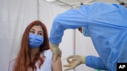 A girl gets a Pfizer BioNTech COVID-19 vaccine in Bucharest, Romania, Wednesday, June 2, 2021. Romania has started the vaccination campaign for children between the ages of 12 and 15. (AP Photo/Andreea Alexandru)