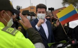 FILE - Colombian Defense Minister Diego Molano, center, gestures to a police officer in Soacha, outskirts of Bogota, March 12, 2021.