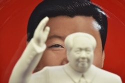 A decorative plate featuring an image of Chinese President Xi Jinping is seen behind a statue of late communist leader Mao Zedong at a souvenir store next to Tiananmen Square in Beijing on February 27, 2018. (Greg Baker (AFP)