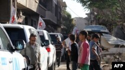 Kendaraan Komite Internasional untuk Palang Merah (ICRC), Bulan Sabit Merah Arab-Suriah dan PBB menunggu di jalanan setelah konvoi bantuan memasuki wilayah yang dikuasai oleh pemberontak di Daraya, Suriah (1/6).