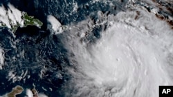 FILE - GOES East satellite image provided by NASA taken at 20:30 UTC, shows the eye of Hurricane Maria as it nears Dominica, Sept. 18, 2017.
