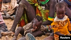 FILE - Women and their children wait to receive relief food supplies near the Kakuma Refugee Camp, northwest of Kenya's capital Nairobi, August 8, 2011. Aid agencies and the Kenyan government set up a new settlement for refugees about 30 kilometers away, in the northwestern town of Kalobeyei, last year.