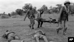 Three Khmer Republican soldiers carry a wounded comrade past two dead soldiers north of Phnom Penh, in 1975. The Khmer communists kept Republican troops busy around the capital while the communists fought for total control of the Mekong River. 