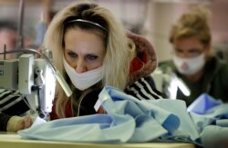 Workers sew scrubs for the National Health Service at the factory of Fashion Enter in London, with the country on lockdown to help curb the spread of the coronavirus, April 3, 2020. The company normally makes fashion garments.