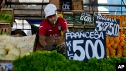 Seorang pedagang menata sayuran di pasar pinggiran Buenos Aires, Argentina, Rabu, 10 Januari 2024. Harga selada adalah 500 peso Argentina per kilogram. (Foto: AP)