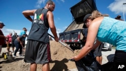 Giovanni Rivera, left, and Nuvia Rivera fill a sandbag, Sept. 12, 2018, in Virginia Beach, Va., as Hurricane Florence moves toward the eastern shore. 