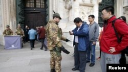 Tentara Italia memeriksa pengunjung di luar gereja Katedral Milan, utara Italia (20/11). Italia dan Swedia meningkatkan pengamanan di wilayah mereka menyusul serangan di Paris minggu lalu.