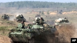 FILE - Belarusian army vehicles drive preparing for war games at an undisclosed location in Belarus, Sept. 11, 2017. Russia and Belarus are holding the annual Zapad war games later this month.