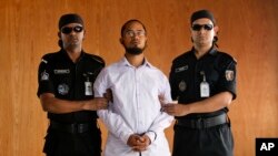 កង​កម្លាំង​ Bangladesh’s Rapid Action Battalion ធ្វើ​ដំណើរ​ជាមួយ​ Farabi Shafiur Rahman (រូប​កណ្តាល) ដែល​ជា​ជន​សង្ស័យ​ក្នុង​ឃាតកម្ម​ទៅ​លើ​អ្នក​សរសេរ​ប្លុក​ជនជាតិ​អាមេរិក​ កាលពី​ថ្ងៃទី២ ខែកុម្ភៈ ឆ្នាំ២០១៥។