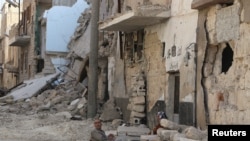 File - Residents rest on the ground near rubble in a damaged neighbourhood in Aleppo, Syria, July 30, 2015. 