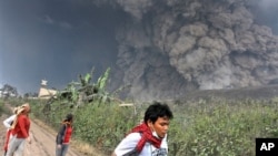 Villagers flee as Mount Sinabung releases pyroclastic flows during an eruption in Namantaran, North Sumatra, Feb. 1, 2014.