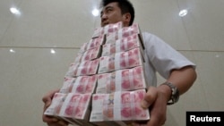 中国山西太原一家银行职员手捧成捆的人民币百元现钞。（资料照片）