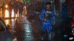 A Maldives policeman charges with a baton towards protesters after the government declared a state of emergency, in Male, Maldives, early Tuesday, Feb. 6, 2018. 