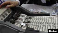 Seorang petugas sedang menghitung uang pecahan seratus dolar di Vietcombank, Hanoi (Foto: dok). Jumlah jutawan di Asia Pasifik meningkat 1,6 persen dibanding tahun lalu.