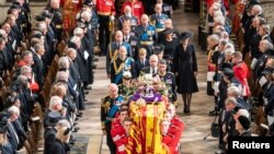 Raja Charles III dan anggota keluarga kerajaan Inggris mengikuti di belakang peti mati Ratu Elizabeth II, yang terbungkus Royal Standard dengan Imperial State Crown dan bola dan tongkat kerajaan, dalam upacara pemakaman kenegaraan di Westminster Abbey, Senin 19 September 2022.