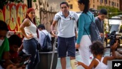 FILE — Eduardo Garcia from Venezuela, on crutches, stands with his family outside the Catholic Charities headquarters, in New York, Aug. 16, 2022. New York City's mayor says he plans to erect hangar-sized tents as temporary shelters for thousands of international migrants who have been bused into the city as part of a campaign by Republican governors to disrupt federal border policies.