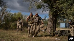 A Ukrainian serviceman helps a comrade during an evacuation of injured soldiers participating in the counteroffensive in a region near the retaken village of Shchurove, Ukraine, on September 25, 2022. 
