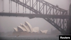 FILE - A boat passes under the Sydney Harbour Bridge and in front of the Sydney Opera House as strong winds and heavy rain hit the city of Sydney, Australia, Nov. 28, 2018. 