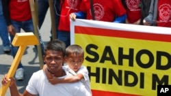 A father carries his son while holding an improvised hammer to symbolize labor during a rally near the Presidential Palace in Manila, Philippines, to pay tribute to workers in celebration of International Labor Day Wednesday, May 1, 2019. 