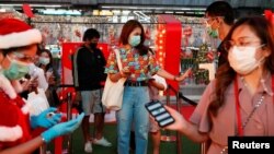 People check their temperature as they visit the Christmas light festival in Bangkok, Thailand, Dec. 21, 2020. 