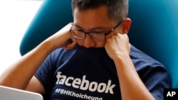 Facebook staff member looks at his computer after the opening ceremony of the company's new office in Hong Kong, July 24, 2014. 