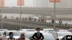 People wearing face masks walk past heavy traffic as Beijing is hit by polluted air and sandstorm, May 4, 2017. Authorities in Beijing issued a blue alert on air pollution as sandstorm swept through the Chinese capital city.