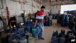 In this Thursday, Jan. 7, 2016 photo, a Palestinian worker carries a gas canister filled only by half, as other bottles wait to be filled at the main gas station in Jebaliya, Gaza Strip. Gas used for heating and cooking in Gaza is in short supply because 