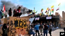 Milisi pro-Iran dan pendukungnya membakar diri saat aksi duduk di depan Kedutaan Besar AS di Baghdad, Irak, Rabu, 1 Januari 2020. (Foto: AP)