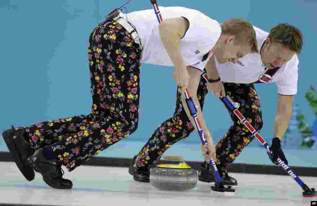 Norway’s Haavard Vad Petersson and Torger Nergaard sweep ahead of the rock during men's curling competition against Canada at the 2014 Winter Olympics, Feb. 14, 2014.