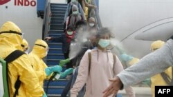 Officials in full protective gear disinfect Indonesian students upon the arrival at Hang Nadim international airport in Batam, following their evacuation from Wuhan, China, due to the coronavirus outbreak. (photo released by Indonesian Embassy)