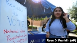 A student gets a voter registration form at Phoenix College on National Voter Registration Day Tuesday, Sept. 24, 2019. (AP Photo/Ross D. Franklin)