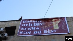 Qiyas İbrahimov binanın üzərində plakat qaldırarkən