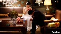 A couple waits to participate in a staged mass wedding, organised as part of a matchmaking event to inspire singles to get married, in a suburban area of Shanghai May 18, 2013. 