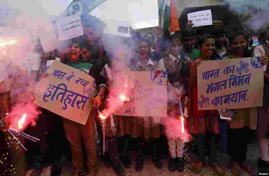 Students light firecrackers and hold placards to celebrate after India's Mars Orbiter successfully entered the red planet's orbit, at a school in the western Indian city of Ahmedabad, Sept. 24, 2014.