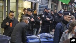 Petugas membawa 3 jenazah aktivis Kurdi yang ditembak tewas di Paris, sementara polisi melakukan penjagaan di lokasi penembakan, Kamis (10/1). 