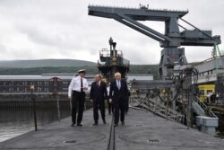 FILE - Britain's Prime Minister Boris Johnson, right, visits the nuclear submarine HMS Victorious with Defence Secretary Ben Wallaceat, centre, and Commander Justin Codd, left, at the Naval Base in Faslane, Scotland, July 29, 2019.