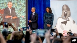 Former President Barack Obama and former first lady Michelle Obama stand on stage together as their official portraits are unveiled at a ceremony at the Smithsonian's National Portrait Gallery, Feb. 12, 2018, in Washington.