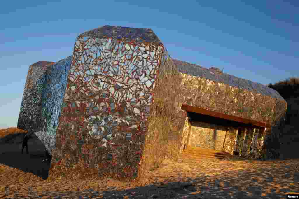 លានដ្ឋាន​មួយ​ដែលបិទទៅដោយ​កញ្ចក់​បែក​ដោយ​សិល្បករ​អនាមិក​ម្នាក់​ត្រូវ​បាន​ឃើញ​អំឡុង​ពេល​ព្រះអាទិត្យ​លិច​នៅ​ឆ្នេរ​ក្នុង​ទីក្រុង​ Leffrinckoucke ប្រទេស​បារាំង។