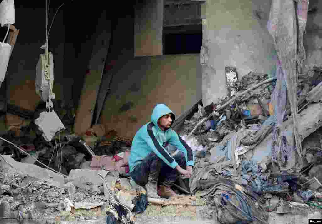A Palestinian sits at the site of an Israeli strike, amid the Israel-Hamas conflict, at the Nuseirat refugee camp in the central Gaza Strip.