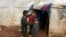 FILE - A father talks with his children outside of a tent at an internally displaced Syrian camp, in northern Aleppo, near the Syrian-Turkish border, Syria, Feb. 17, 2021.
