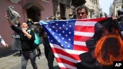 FILE - Protesters against Peruvian President Martin Vizcarra, who faces an impeachment vote, carry a U.S. flag with the letter Q, referring to QAnon, near Congress in Lima, Peru, Nov. 9, 2020. 