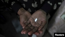 FILE - An AIDS patient is seen holding an antiretroviral drug.