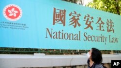 រូបឯកសារ៖ ស្ត្រី​ម្នាក់​ដើរ​កាត់​បដា​ច្បាប់​សន្ដិសុខ​ជាតិ​សម្រាប់​ទីក្រុង​ហុងកុង ក្នុង​ទីក្រុង​ហុងកុង ថ្ងៃទី៣០ ខែមិថុនា ឆ្នាំ២០២០។ ប្រទេស​ចិន​បាន​អនុម័ត​ច្បាប់​នេះ​ ដែល​នឹង​អនុញ្ញាត​ឲ្យ​អាជ្ញាធរ​អាច​បង្ក្រាប​សកម្មភាព​ផ្ដួល​រំលំ​រដ្ឋាភិបាល​ក្នុង​ទីក្រុង​ហុងកុង​បាន។ 