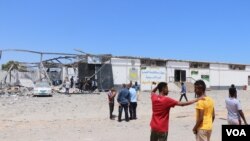 FILE - After the bombing of the detention center that killed more than 50 civilians and wounded more than 130, migrants watch authorities search for human remains, near Tripoli, Libya, July 3, 2019. (H. Murdock/VOA)
