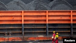 Workers walk near a tugboat carrying coal barges at a port in Palembang, South Sumatra province, Indonesia, Jan. 4, 2022, in this photo taken by Antara Foto.