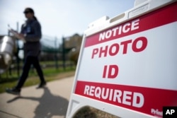 FILE - A Super Tuesday voter walks past a sign requiring photo identification at a polling location in Mount Holly, North Carolina, March 5, 2024.